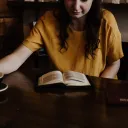 a woman sitting at a table with an open Bible and a coffee mug