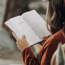 a woman sitting with an open Bible in her hands