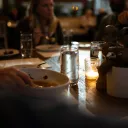 a group of people gathered around a dinner table, lit by candlelight