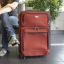 a woman sitting beside a suitcase and holding a passport