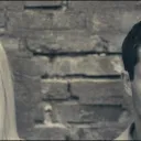 half of a woman's face and half of a man's face in grayscale separated by an expanse of brick wall