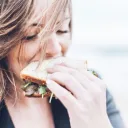A young woman eating a healthy looking sandwich,