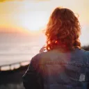 A woman looking at sunset over a body of water.