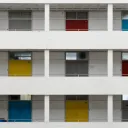 Outside of building with several floors featuring different colored doors.