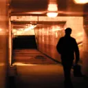 A man walking down a tunnel hallway.