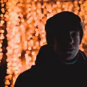 A young man standing in front of red lights.