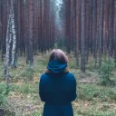 A young woman looking into a forest.