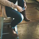 A woman sitting on a bench adjusting her shoes.