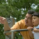 A dad and son playing at a park.