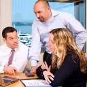 A group of people working together at a table using laptops.