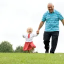 A grandfather holding his little grandaughter's hands.
