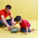 A father and son counting pennies from a glass jar.