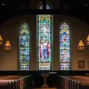 Inside a large church with stain glass windows.