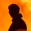 A silhouette of a man with smoke and flames around him.