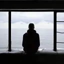 A teen sitting in abandoned window frame of an old house.