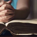 A person with their hands on top of a Bible.