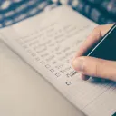 A person making a list with checkbox on paper.