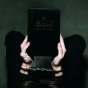 A person holding a Bible while their hands are wearing shackles.
