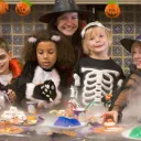 A mom and four kids eating Halloween treats.