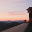 A young man watching the sun set from an observation deck.