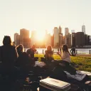 A group of friends on blanket in a park talking.