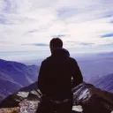 A man standing on top of a mountain peak.
