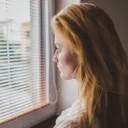 A young woman staring out a window.