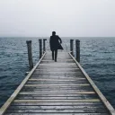A man walking on a pier going out into the water.