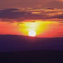 A sun setting over a hill.