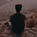 A young man sitting on a rock cliff