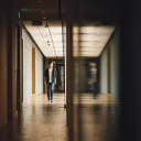 A young guy walking in the hallway of a building.