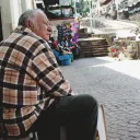 A old man sitting on a bench in an old village.