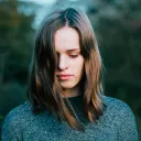A young woman holding her head down facing the ground.