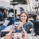 A woman taking a photo of another women with a smartphone.