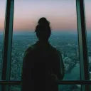 A woman looking outside of window of tall building.