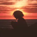 A silhouette of young woman with the sun setting in the background.