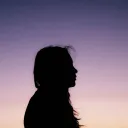A silhouette of young woman with the sun setting in the background.