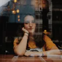 A young woman sitting with her arms on a counter looking through a window.