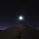 A person with a head lamp shining bright in the darkness.