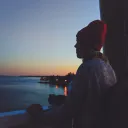 A woman looking out over a body of water at sunset.