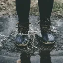 A person wearing boots standing in a puddle.