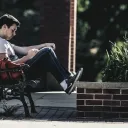 A man sitting on a park bench reading.
