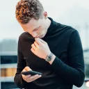 A young man looking down at his smartphone.
