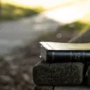 A Bible laying on a park bench.