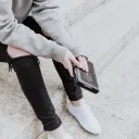 A woman sitting on concrete steps holding a Bible.