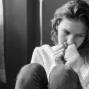 A sad woman sitting on the floor.