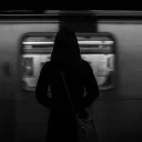 A woman standing by a subway train as it passes by.