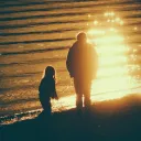 A dad and his children walking on the beach as the sun is setting.