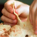A hand tearing about some flat bread.