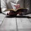 A person reading a Bible at a table.